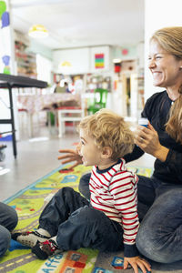 Happy teacher with student looking away in kindergarten