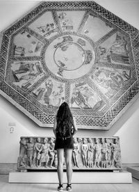 Rear view of woman standing against wall in museum