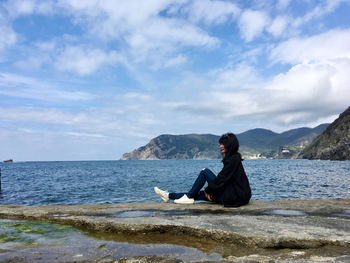 Man sitting on shore against sky