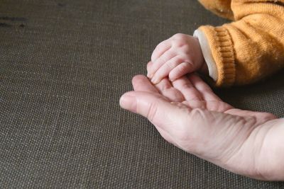 Cropped hands of parent and baby at home