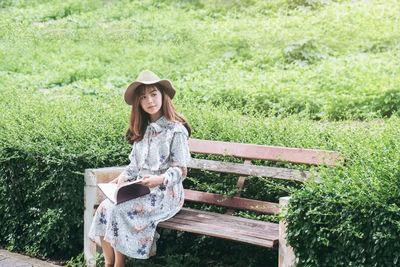 Woman with book sitting on bench at park