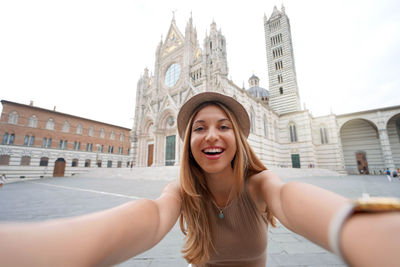 Holidays in italy. brazilian girl takes selfie picture with smartphone in siena, tuscany, italy.