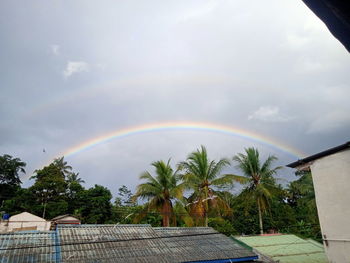 Scenic view of rainbow over building and trees against sky