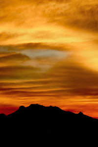 Scenic view of silhouette mountains against orange sky