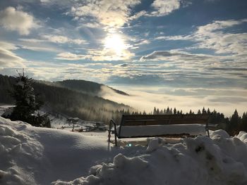 Snow covered landscape against sky during sunset