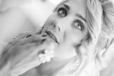 Tilt shot of beautician applying make-up on bride