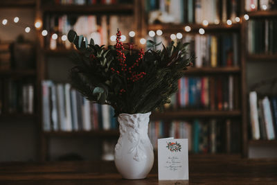 Flower vase with greeting card on table