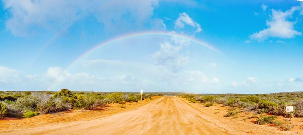Scenic view of rainbow over road against sky