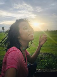 Side view of woman on field against sky