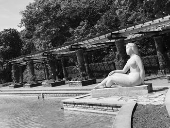 Man sitting by statue against trees