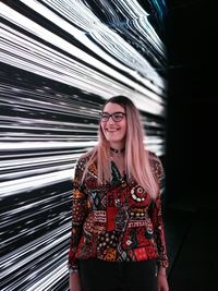 Smiling young woman standing against wall