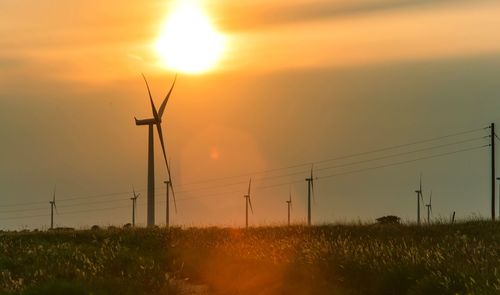 Electricity pylon on field against sky during sunset