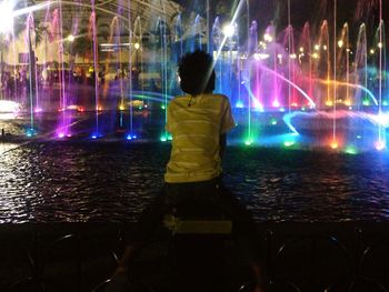 Rear view of woman standing against sky at night