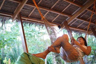 Woman using mobile phone while lying in hammock