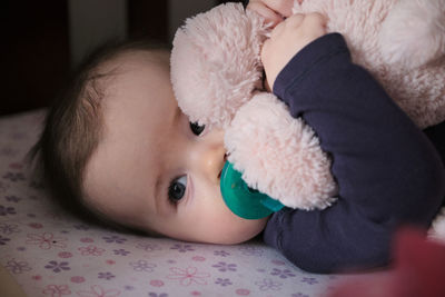 Infant on the bed with his pacifier and plush toy