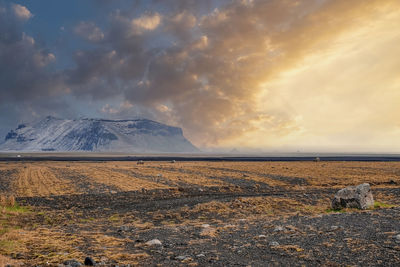 View of mountain on lava sand in highland against cloudy sky during sunset