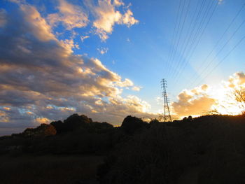 Low angle view of silhouette electricity pylon against sky