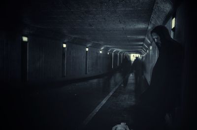 Lonely man standing in dark tunnel