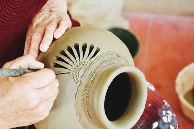 Close-up of person hands carving on earthenware