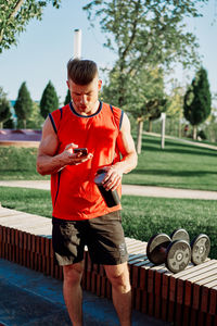 Side view of young man with arms outstretched standing in park