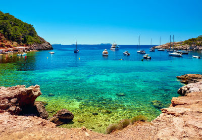 Boats on cala salada against blue sky