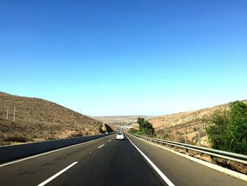 Empty road against clear blue sky