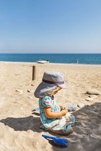 Rear view of hat on beach against sky