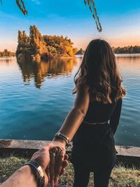 Woman with arms raised on lake against trees