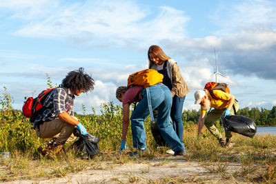 Rear view of friends walking on field against sky