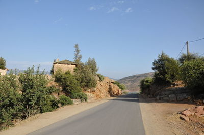 Road amidst trees against clear sky