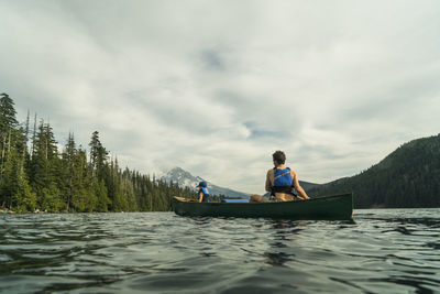 A young girl rides in a canoe with her dad on lost lake in oregon.