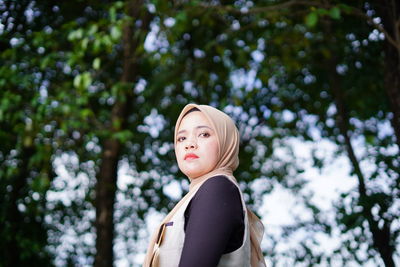 Portrait of young woman against trees