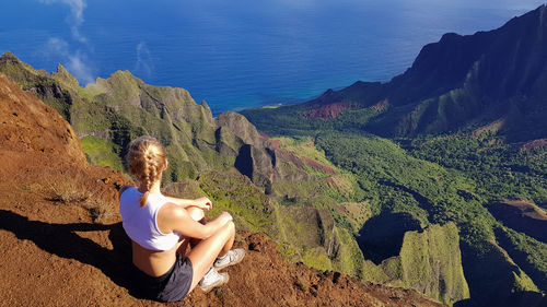 Woman sitting on rock looking at mountains