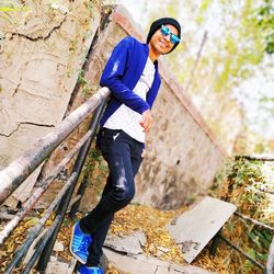 Man wearing sunglasses while standing by railing against wall