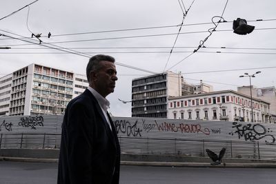 Side view of man standing against buildings in city