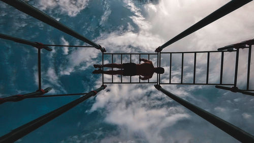 Low angle view of man exercising against cloudy sky