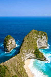 Rock formation on sea shore against blue sky