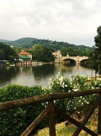 Bridge over river by buildings against sky