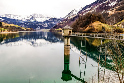 Scenic view of lake by snowcapped mountains against sky