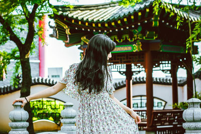 Rear view of woman walking in temple outside building