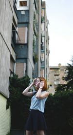 Low angle view of woman standing against buildings