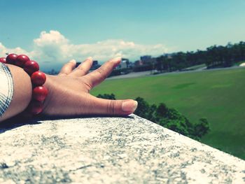 Close-up of hand on wall against sky