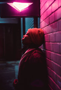Side view of woman standing against illuminated wall