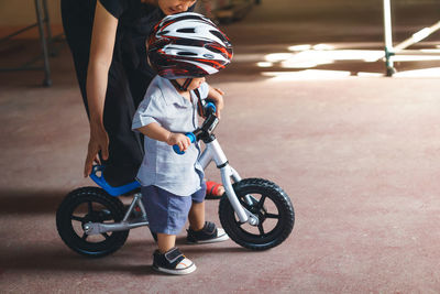 Mother teaching cycling to son on floor