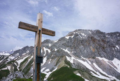 Cross on snow covered mountain against sky