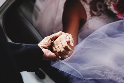Man holding hands of bride while sitting in car