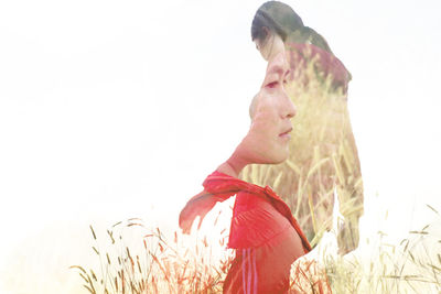 Side view of young woman standing against sky
