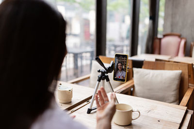 Young caucasian millennial or gen z woman with long brunette hair streaming with phone on tripod