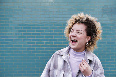 Happy curly haired woman looking away