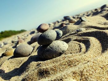 Close-up of pebbles on sand at beach against sky